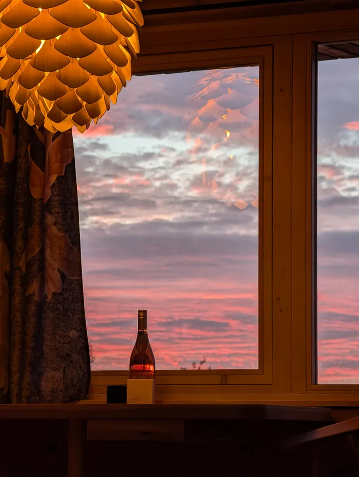 Lampa ve tvaru šišky a růžové nebe za oknem tiny house U Lesa