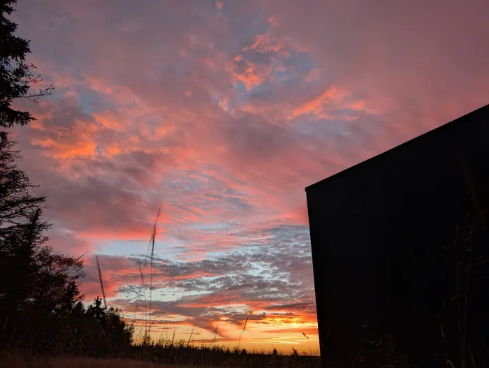 Růžová obloha při západu slunce nad tiny house U Lesa