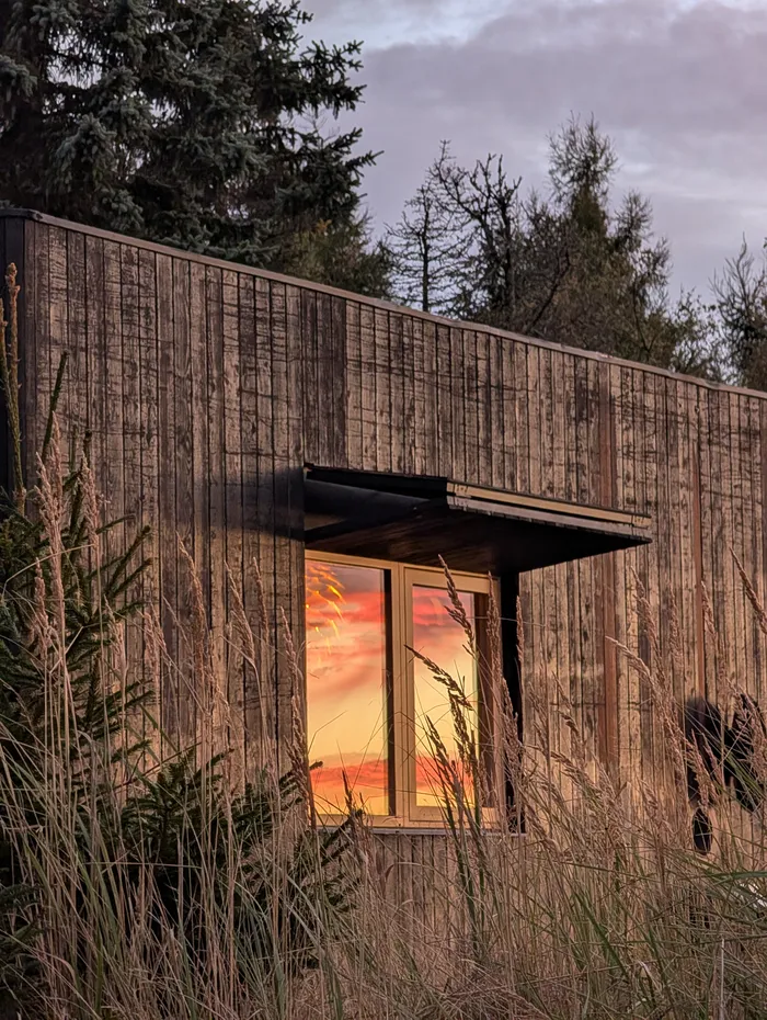 Západ slunce odražený v okně tiny house U Lesa