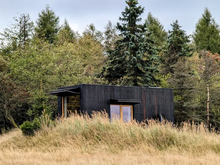 Tiny house U Lesa z tmavého dřeva pod vysokými smrky