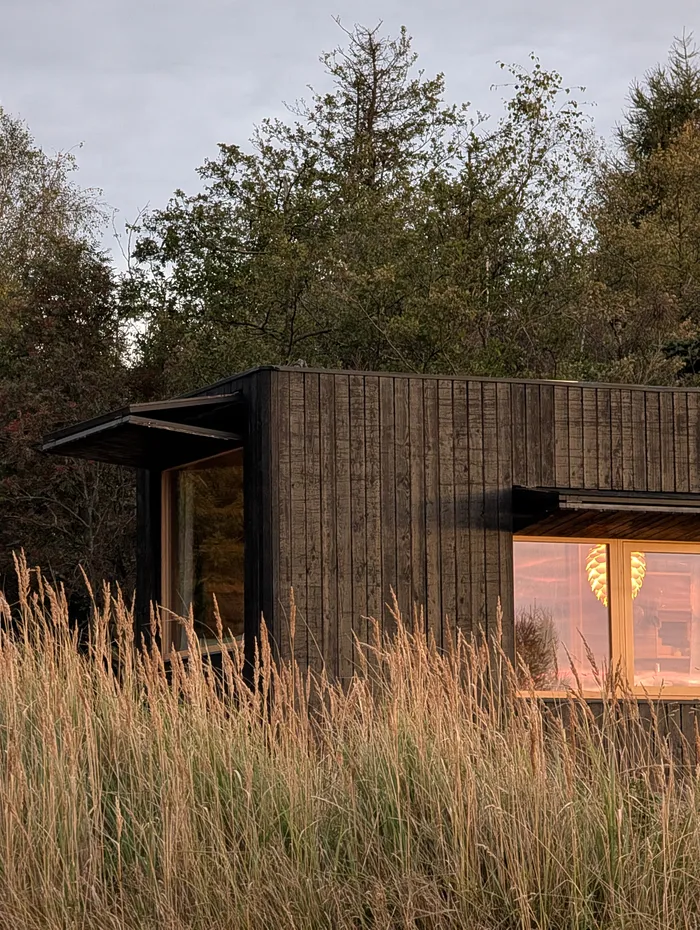 Rozsvícená okna tiny house U Lesa za soumraku