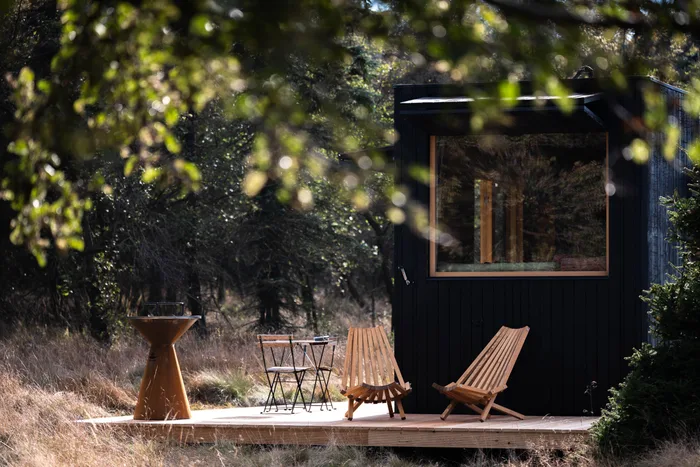 Terasa tiny house U Lesa s lehátky, stolkem a grilem pod větvemi stromu