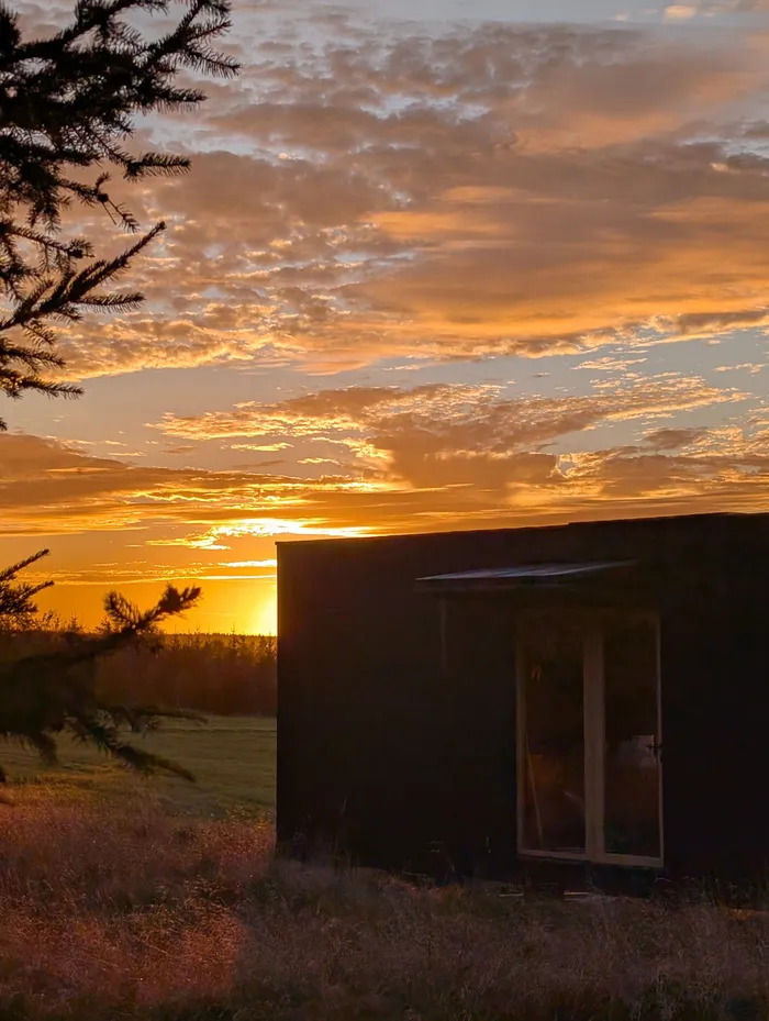 Západ slunce nad loukou u tiny house U Lesa