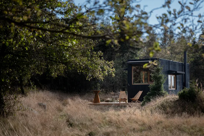 Tiny house U Lesa s terasou a lehátky na kraji lesa, pohled přes větve stromu