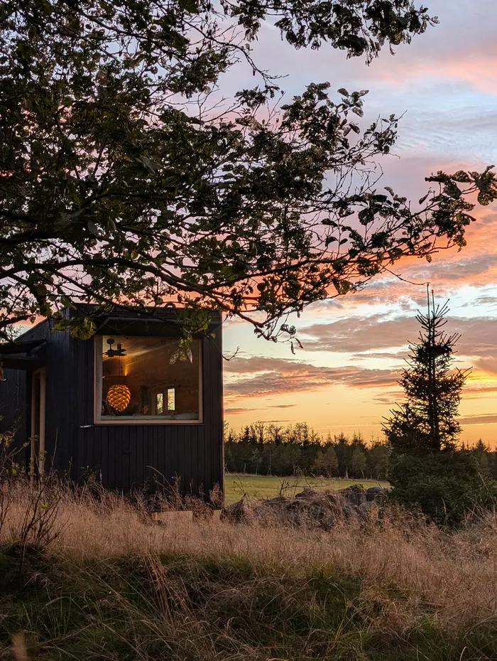 Rozsvícené okno tiny house U Lesa při západu slunce