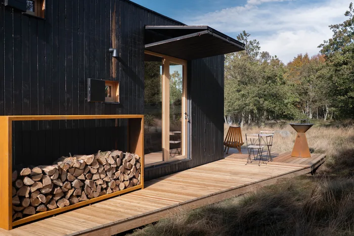 Dřevník, prosklený vchod a terasa s grilem u tiny house U Lesa