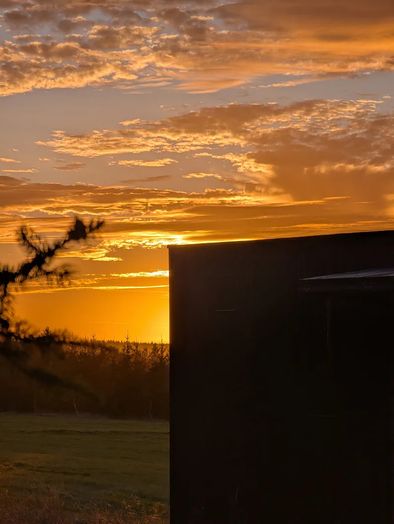 Západ slunce nad loukou vedle tiny house U Lesa